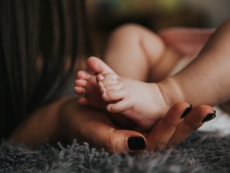 female hand holding a baby foot illustrating parent care and consent