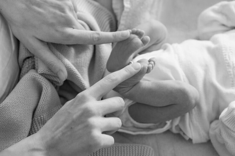 greyscale picture of newborn baby feet with a womans index fingers touching each food, highlighting the issue at hand 90 Day Fiancé star Ariela