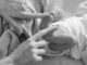 greyscale picture of newborn baby feet with a womans index fingers touching each food, highlighting the issue at hand 90 Day Fiancé star Ariela