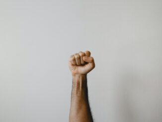 fist raised in the air on grey background, illutrating the need for help for intaction.org call for help stop profit from circumcision