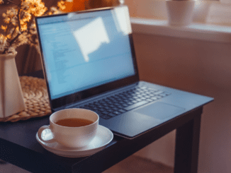 a steaming cup of black tea in a white cup and acucer, on a black coffee table next to an open laptop, illustrating online participaents of the Conference & AGM should arrange thier own refreshment